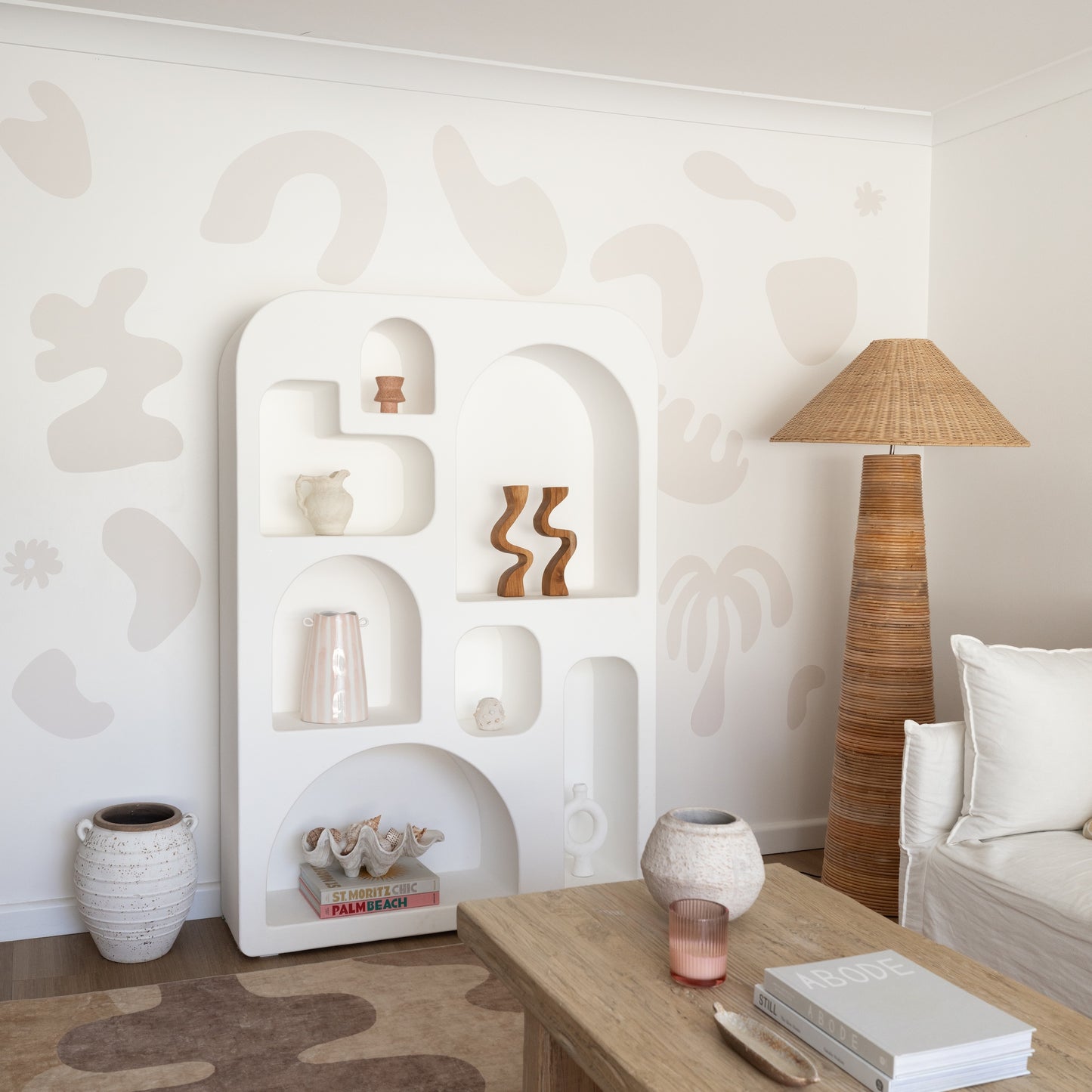 Modern living room with a white shelving unit, wooden coffee table, and decorative lamp.