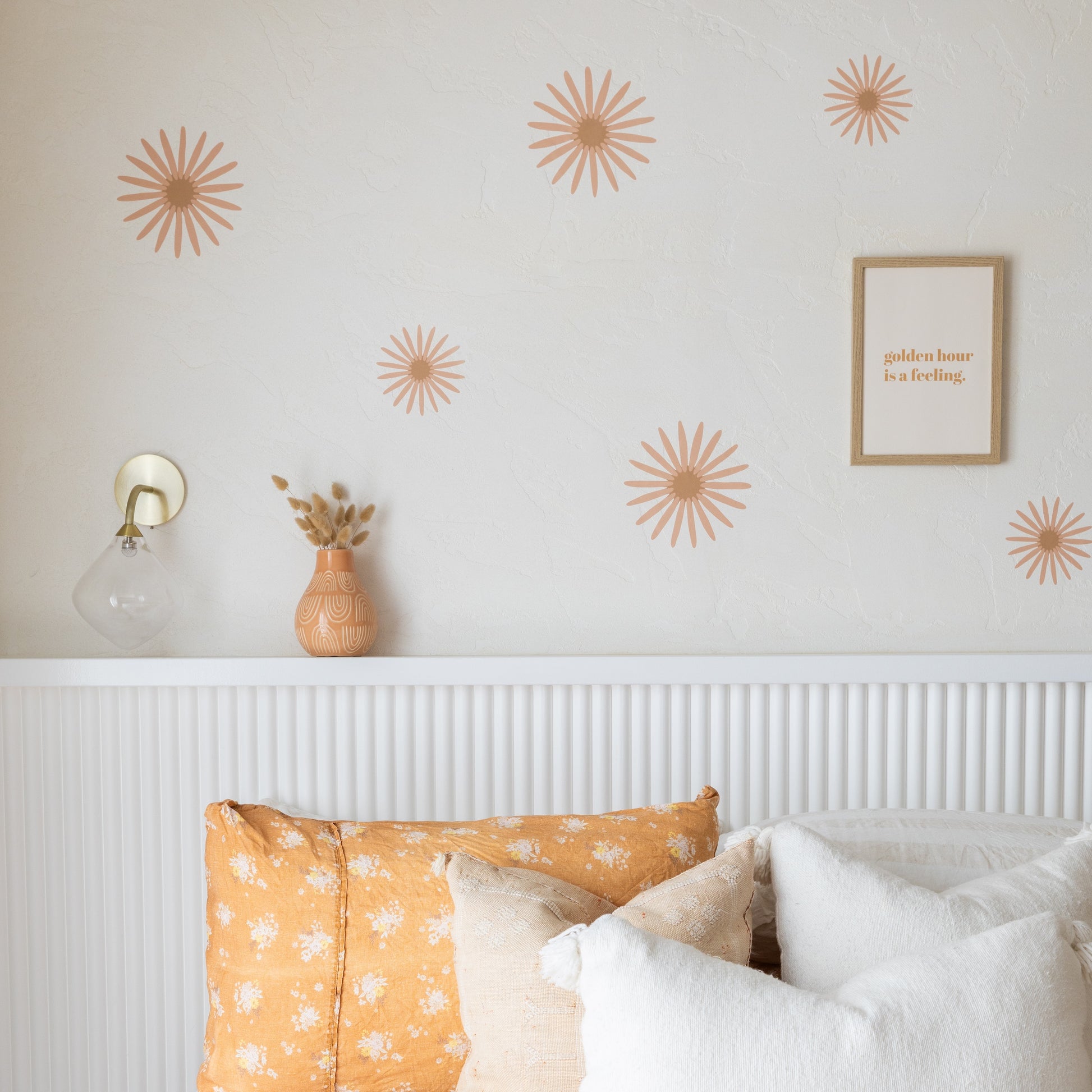 Decorative flower wall stickers on a bedroom wall with a bed and lamp in the foreground.