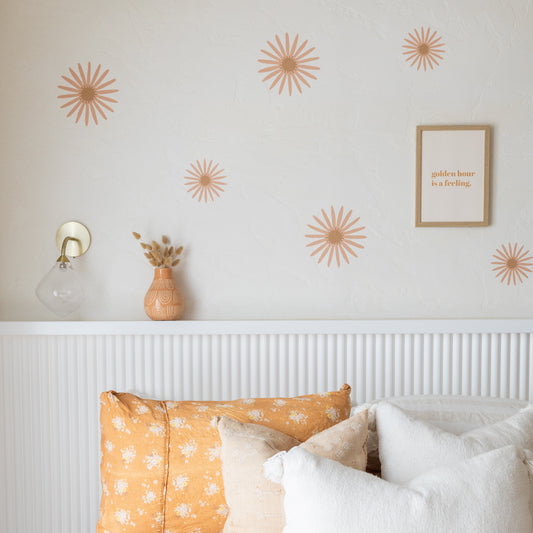 Decorative flower wall stickers on a bedroom wall with a bed and lamp in the foreground.